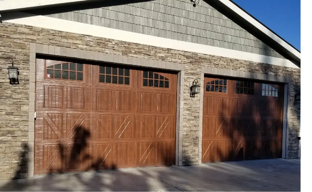 Two wood-grain carriage-house garage doors set in a stacked-stone garage front