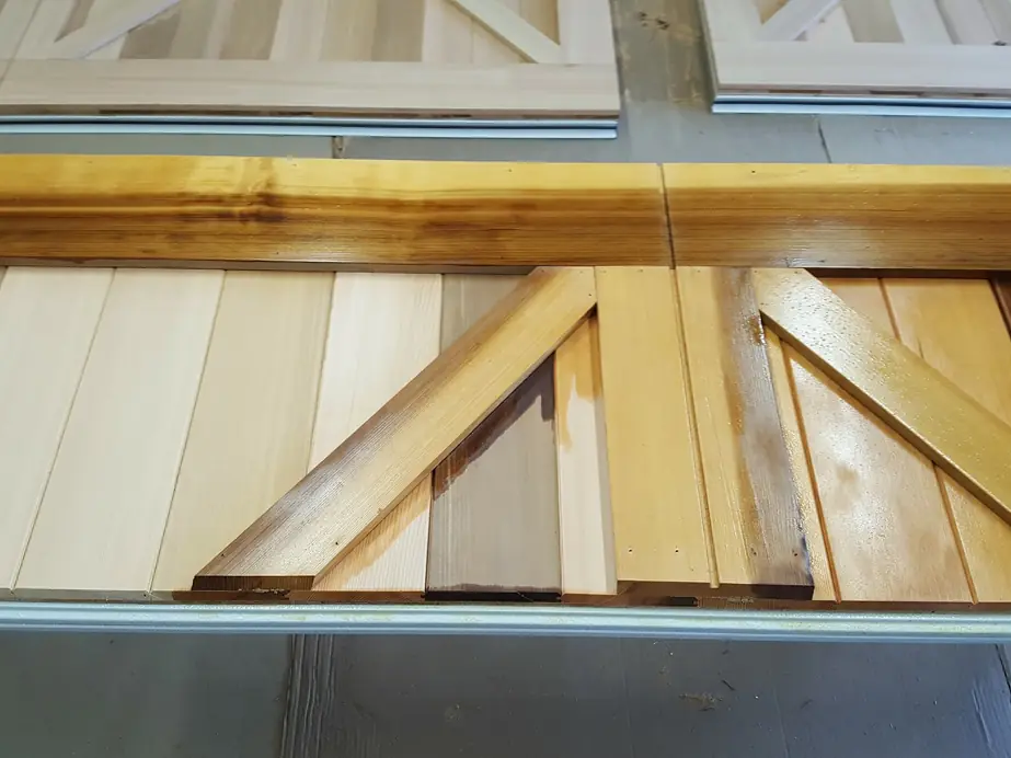 Close-up of a cedar carriage door: tongue-and-groove planks with an applied cross brace